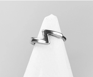 Vue détaillée d'une bague minimaliste en acier inoxydable en forme d'éclair sur support