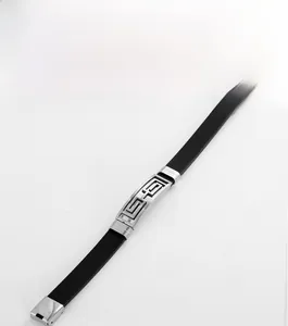 Detail of men's black silicone bracelet featuring a Greek key pattern steel centerpiece