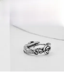 Macro shot of silver-toned vintage rose and thorn stud earring with intricate details