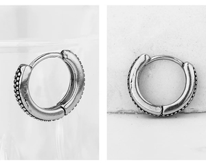 Macro detail of silver vintage stainless steel hoop earrings with textured beaded pattern