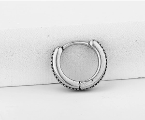 Detail of retro silver hoop earring with embossed dots and secure buckle closure