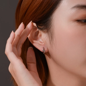 Gros plan d'une boucle d'oreille éclair minimaliste en acier argenté portée sur l'oreille