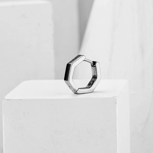Minimalistische silberne Sechseck-Ohrringe auf weißem geometrischem Stein-Hintergrund