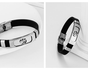Macro detail of stainless steel bracelet with hollow crown emblem on black silicone strap