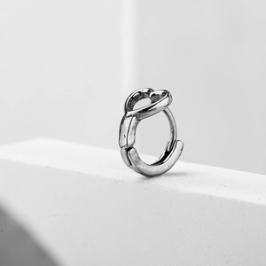 Minimalist silver stainless steel heart hoop earring on white geometric pedestal