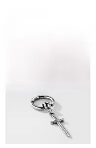 Macro detail of silver-toned stainless steel sword pendant hanging from a polished hoop earring
