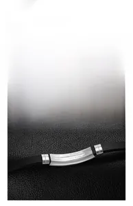 Close-up of minimalist stainless steel bracelet with black leather strap and engraving