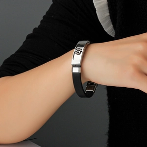 Men's hollow stainless steel floral charm bracelet with black silicone band on wrist