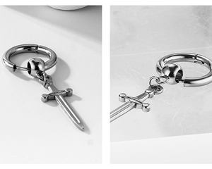 Detail of silver stainless steel hoop earrings featuring a small punk sword pendant