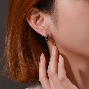 Minimalist retro stainless steel hoop earrings with black textured grooves on model