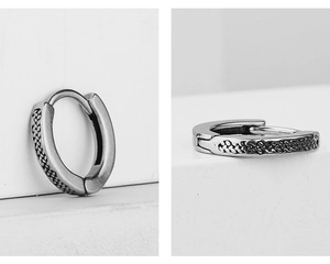 Detail of vintage silver huggie earrings with a black braided texture and snap closure