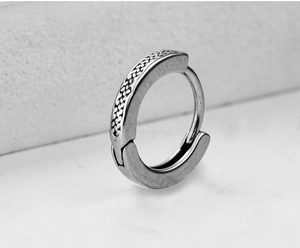 Detailed close-up of silver-tone huggie earrings featuring intricate braided texture