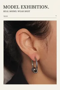 Close-up of unisex cross-style earrings with a textured pendant on model's ear