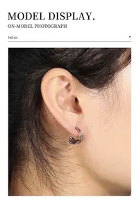 Detailed view of gunmetal dragon claw huggie earrings worn on ear for model display