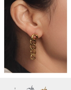 Close-up of golden Cuban link chain earrings on model showing modern metallic style