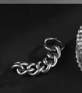 Détail macro d'une boucle d'oreille créole en acier argenté avec maillons gourmette