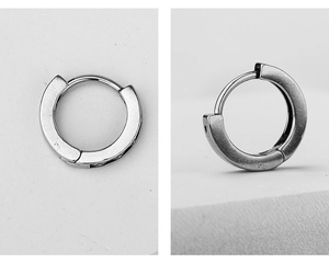 Detailed macro view of minimalist stainless steel huggie earrings with hinged closure