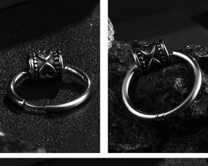 Detail of gothic stainless steel hoop earring with engraved heart and cylinder charm