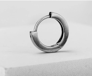 Macro view of vintage style stainless steel huggie earring with brushed metal texture