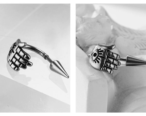 Detail view of silver punk dragon style earring with hand and spike on a stone display