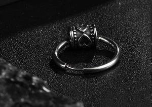Macro shot of vintage steel hoop earring with engraved heart bead on black texture