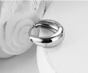 Macro shot of minimalist silver polished metal huggie hoop earring with mirror finish