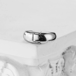 Polished silver metal hinged hoop earring on a white stone display in minimalist style