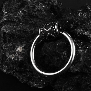 Stainless steel hoop earrings with engraved heart cylinders on dark volcanic rock