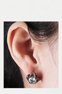 Close-up of a silver crown-shaped earring with a clear round zircon on earlobe