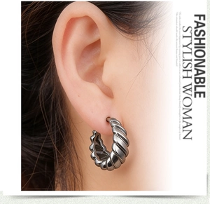 Detail of silver hoop earrings with spiral texture shown on a model for scale and fit