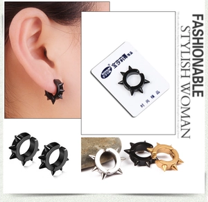 Gros plan de boucles d'oreilles punk en acier titane avec pointes en noir, argent et or