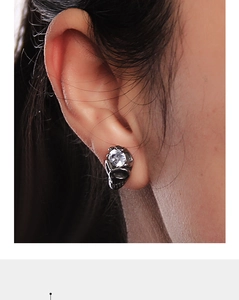 Detailed view of skull-shaped stud earring with cubic zirconia on a person's ear