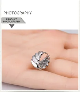 Detailed macro shot showing ribbed texture on silver stainless steel huggie earrings