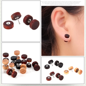 Détail des boucles d'oreilles haltères en bois montrant la texture et la structure