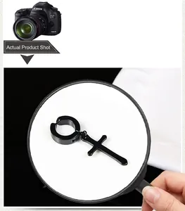 Detail view showing black titanium steel cross clip earring through a magnifying glass
