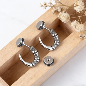 Detailed macro view of silver stainless steel dragon claw punk earrings on a wooden box