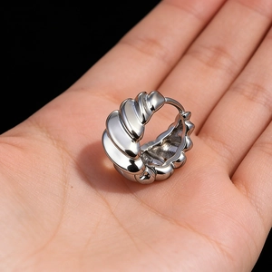 Men's silver stainless steel hoop earring with striped pattern held in hand