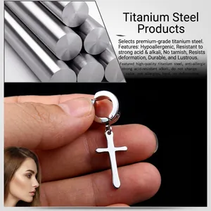 Close-up of polished titanium steel cross clip-on earring held by hand