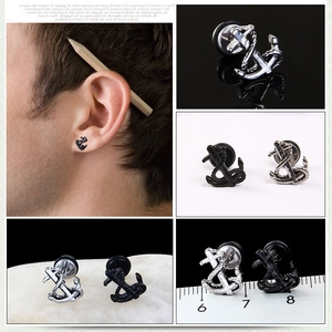 Macro detail of nautical anchor stud earrings in polished silver and black steel finish