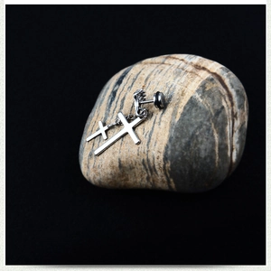 Détail de boucles d'oreilles double croix argentées avec chaîne sur fond de pierre