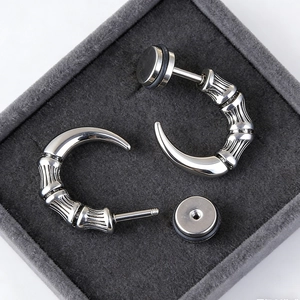 Macro shot of silver dragon claw earrings with polished metal texture on velvet