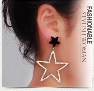 Detail of gold five-point star earrings with pave set diamonds on a female model