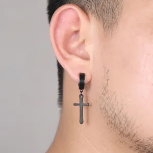 Close-up of black stainless steel cross drop earring worn on ear for pierced ears