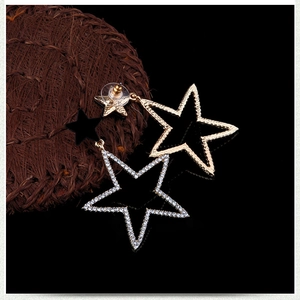 Close-up of gold star earrings with pavé rhinestones and a black star pendant