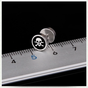 Macro shot of 10mm punk skull barbell earring in polished steel next to a ruler