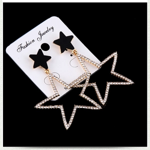 Detail shot of gold star drop earrings with sparkling rhinestones and black star stud
