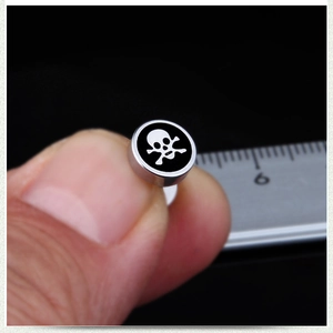 Macro view of stainless steel skull stud earring measuring approximately 8-10mm diameter