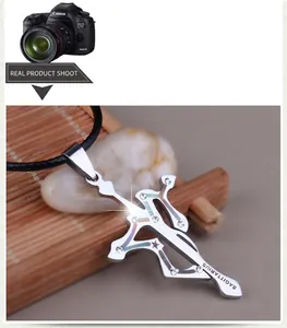 Macro shot of silver Sagittarius cross pendant with white rhinestones and black cord