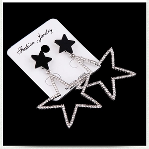 Close-up of star-shaped earrings with black studs and diamond-encrusted silver hoops