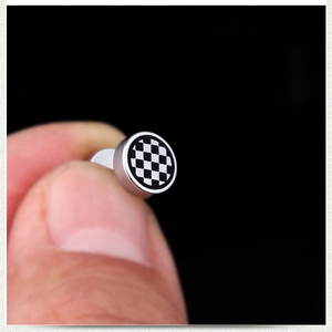 Gros plan d'un clou d'oreille en acier inoxydable argenté avec motif de damier noir et blanc